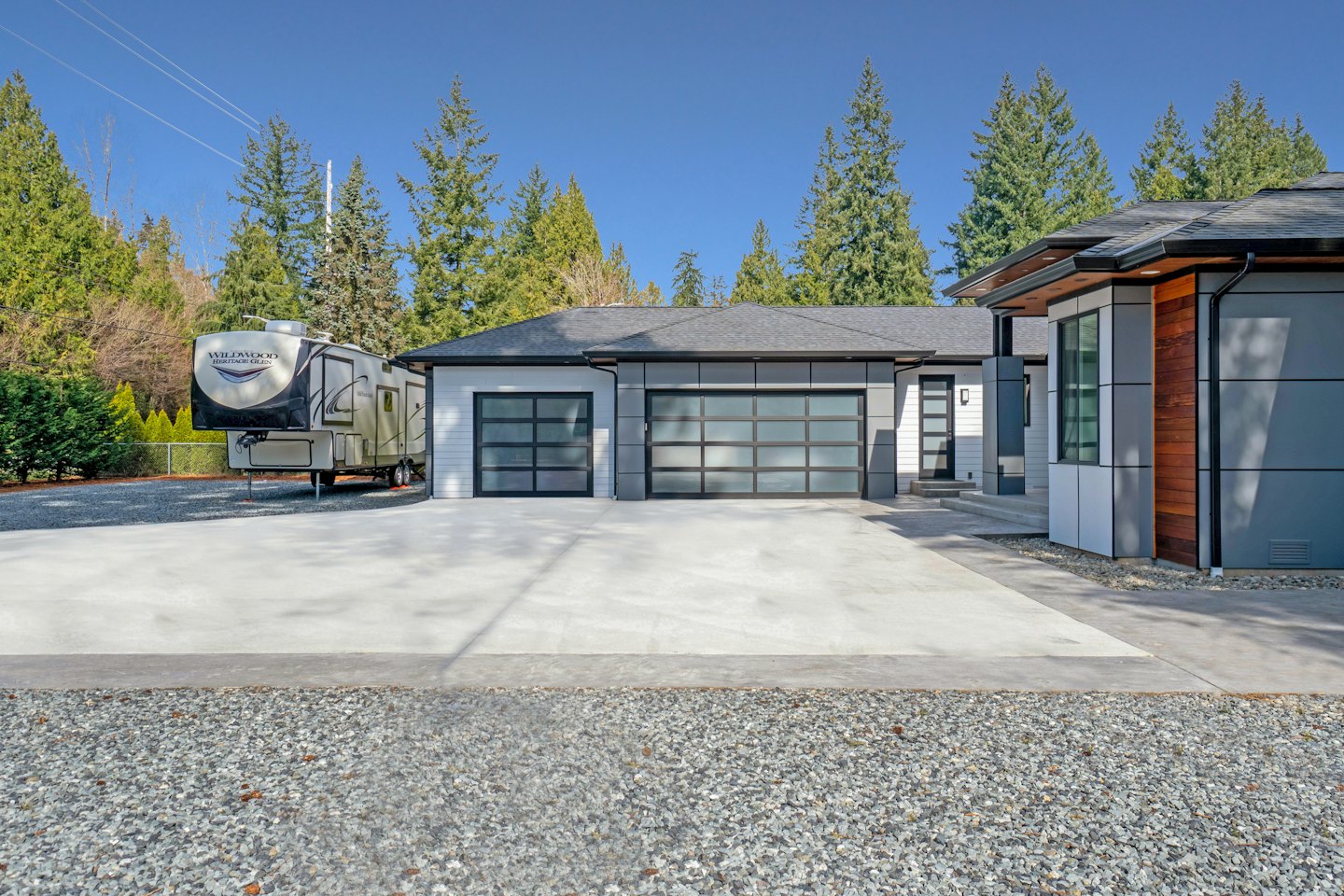 Modern grey and white house with RV parked nearby.